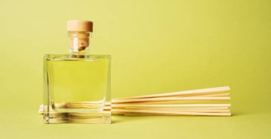 aroma reed fragrance diffuser with rattan sticks on light green background clipart