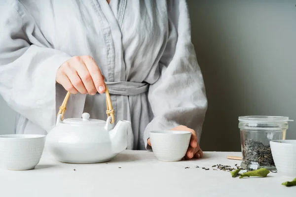 Female hands holding teacup during tea ceremony with selective focus. Asian food theme background. Brewing and Drinking tea.