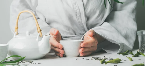 Female hands holding teacup during tea ceremony with selective focus. Asian food theme background. Brewing and Drinking tea.