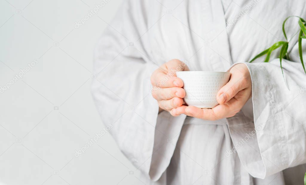 Woman holding in hands cup of tea on light background 