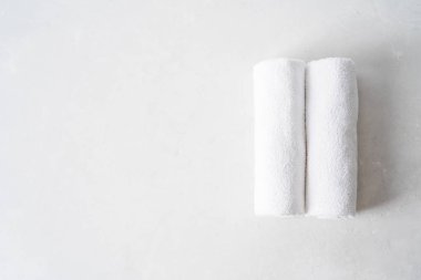 iki beyaz kabarık havlu içine bükülmüş hafif beton arka plan üzerinde rulo 