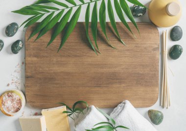 Beyaz havlu, koku koku, organik sabunlar, pembe tuz ve palm çerçeve kompozisyonu ile ahşap tahta ışık yüzey üzerinde bırakır.