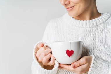 Kadın sıcak örme yün kazaklı beyaz kupa çay poşeti sevgiyle, Sevgililer günü mockup kalpli elinde tutan görünümünü kapat