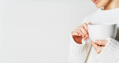 Sıcak örme yün ışık kazaklı beyaz kupa elinde tutan güzel bir kadın. Uzun geniş afiş kopya alanı ile.