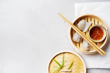 Geleneksel Çince köfte Dim toplamları Har Gow sos ve yemek çubukları ile bambu gemi içinde ışık arka plan üzerinde buğulama