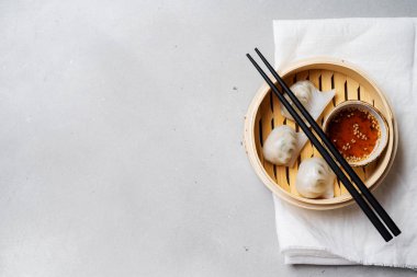Geleneksel Çince köfte Dim toplamları Har Gow sos ve yemek çubukları ile bambu gemi içinde ışık arka plan üzerinde buğulama
