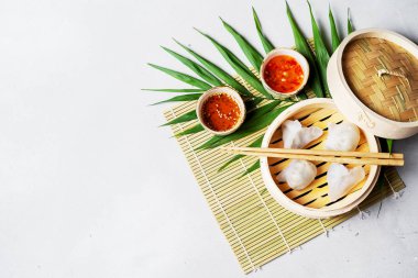 Geleneksel Çince köfte Dim toplamları Har Gow sos ve yemek çubukları ile bambu gemi içinde ışık arka plan üzerinde buğulama