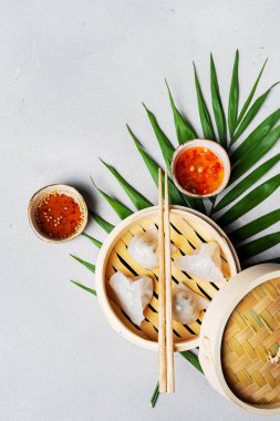 Geleneksel Çince köfte Dim toplamları Har Gow sos ve yemek çubukları ile bambu gemi içinde ışık arka plan üzerinde buğulama