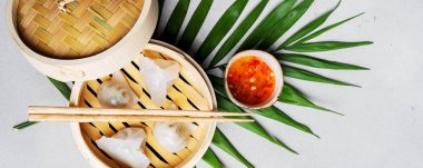 Geleneksel Çince köfte Dim toplamları Har Gow sos ve yemek çubukları ile bambu gemi içinde ışık arka plan üzerinde buğulama