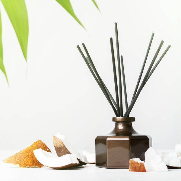 Аромат тростниковой диффузер бутылка дома аромат с палочками ротанга и свежие кусочки кокоса на белом фоне
 