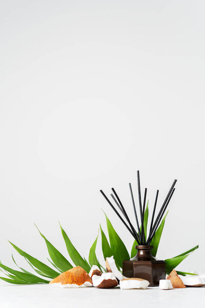 Аромат тростниковой диффузер бутылка дома аромат с палочками ротанга и свежие кусочки кокоса на белом фоне
 