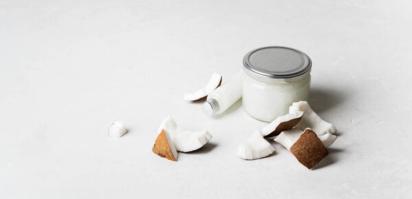 Набор с органическим здоровым кокосовым маслом в стеклянную банку и бутылку со свежими кусочками кокоса на белом фоне
