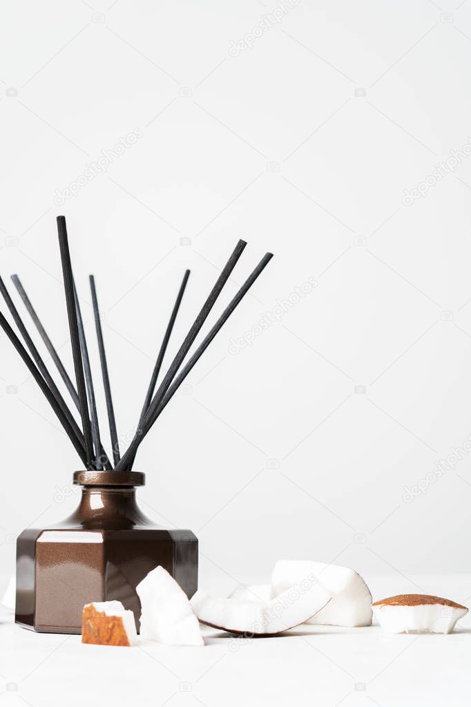 Aroma reed diffuser bottle home fragrance with rattan sticks and fresh coconut pieces on white background 