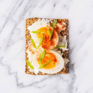 Ana sayfa görünümü Superfood protein ekmek üstüne lezzetli Topingler ile: soğan ve kırmızı biber üzerine krem peynir ile haşlanmış yumurta yalan üzerinde mermer serface.