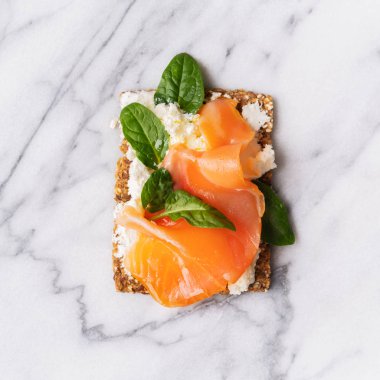Ana sayfa görünümü Superfood protein ekmek üstüne lezzetli Topingler ile: füme somon, ıspanak, mermer serface üzerine krem peynir. 