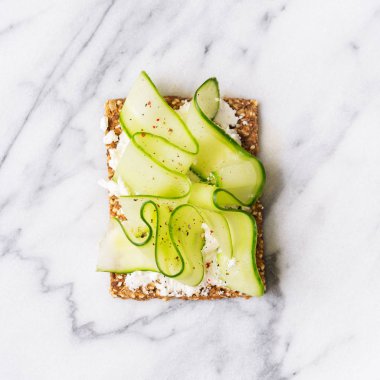 Ana sayfa görünümü Superfood protein ekmek üstüne lezzetli Topingler ile: salatalık krem peynir ile yalan üzerinde mermer serface.