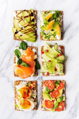 protein tost lezzetli avokado, somon balığı, yumurta, sebze, domates, otlar, çam fıstığı, ayçiçeği tohumu ve krem peynir mermer yüzeyi ile