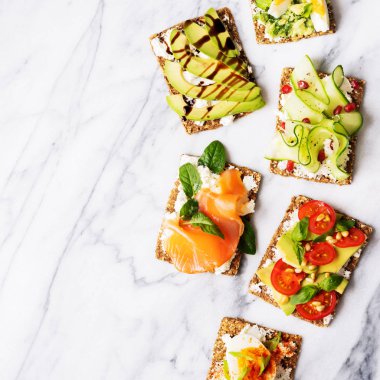 protein tost lezzetli avokado, somon balığı, yumurta, sebze, domates, otlar, çam fıstığı, ayçiçeği tohumu ve krem peynir mermer yüzeyi ile