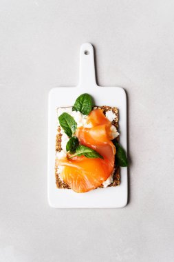 Ana sayfa görünümü Superfood protein ekmek üstüne lezzetli Topingler ile: füme somon, ıspanak, mermer serface üstüne beyaz tahta üzerine krem peynir. 