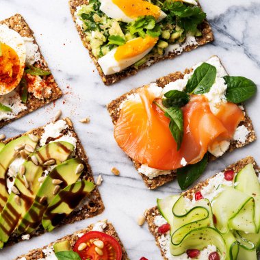 protein tost lezzetli avokado, somon balığı, yumurta, sebze, domates, otlar, çam fıstığı, ayçiçeği tohumu ve krem peynir mermer yüzeyi ile