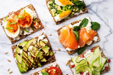 protein tost lezzetli avokado, somon balığı, yumurta, sebze, domates, otlar, çam fıstığı, ayçiçeği tohumu ve krem peynir mermer yüzeyi ile