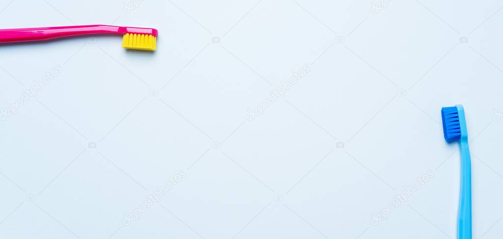 Colorful toothbrushes with bright color bristles on light pastel blue background