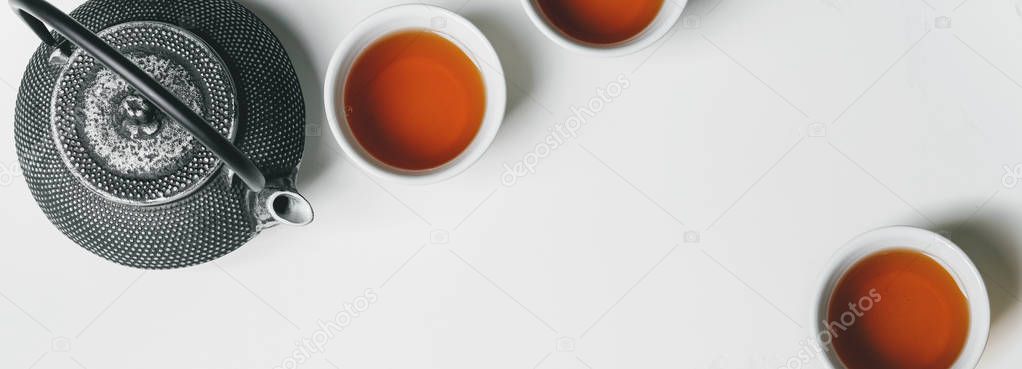Oriental Asian tea set with white cups of tea and cast iron teapot on white background