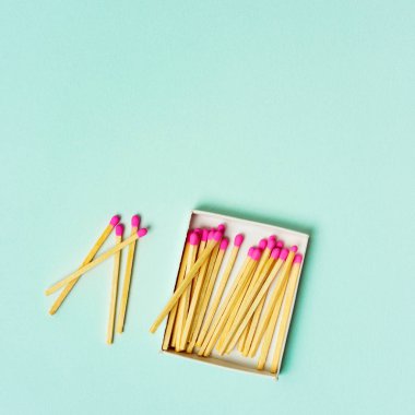 Kibrit kutusu turkuaz pastel zemin üzerine saçılan parlak ahşap maçlar