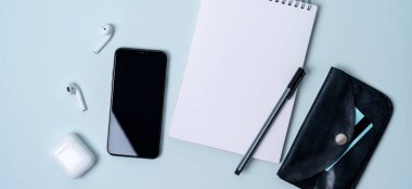 akıllı telefon, kablosuz kulaklık, not defteri, açık mavi renkli kredi kartı ile cüzdan ile kompozisyon 