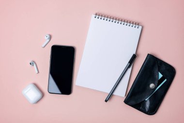 akıllı telefon, kablosuz kulaklık, not defteri, cüzdan, kredi kartı ile açık pembe renkli ile kompozisyon