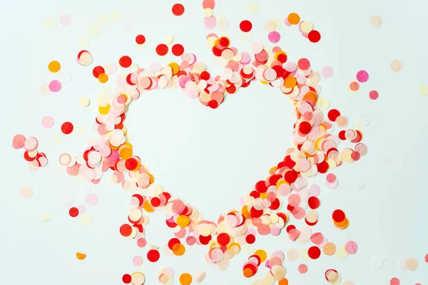 Heart shaped colorful confetti on pastel background