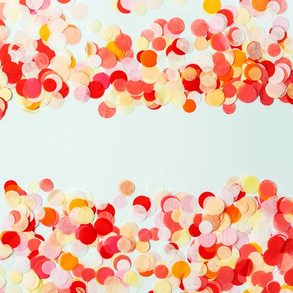 パステル調の背景に赤とオレンジのお祝いの紙吹雪で作られたカラフルなフレーム — ストック写真