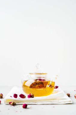 Kurutulmuş pembe ile bitkisel çay şeffaf çaydanlık gri arka planda tomurcuk gül