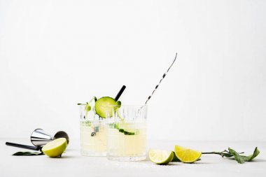 Beyaz arka planda kireç dilimleri ve mikro yeşillikler ile süslenmiş salatalık ile taze kokteyl çift gözlük