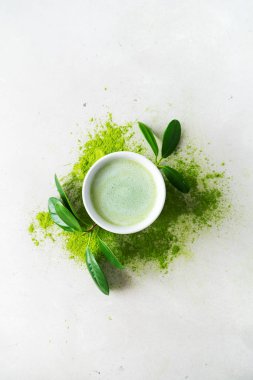 Beton arka plan üzerinde dağınık toz çay üzerinde yaprakları ile süslenmiş Japon Matcha çay bawl ile Kompozisyon