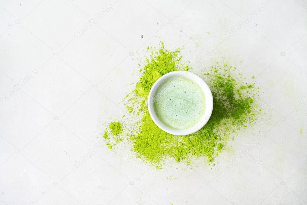 Bawl with Japanese Matcha tea over scattered green powder tea on concrete background