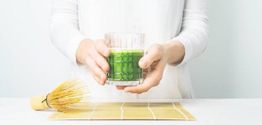 Beyaz arka planda Matcha çayı ile cam tutan kadının yakın görünümü 