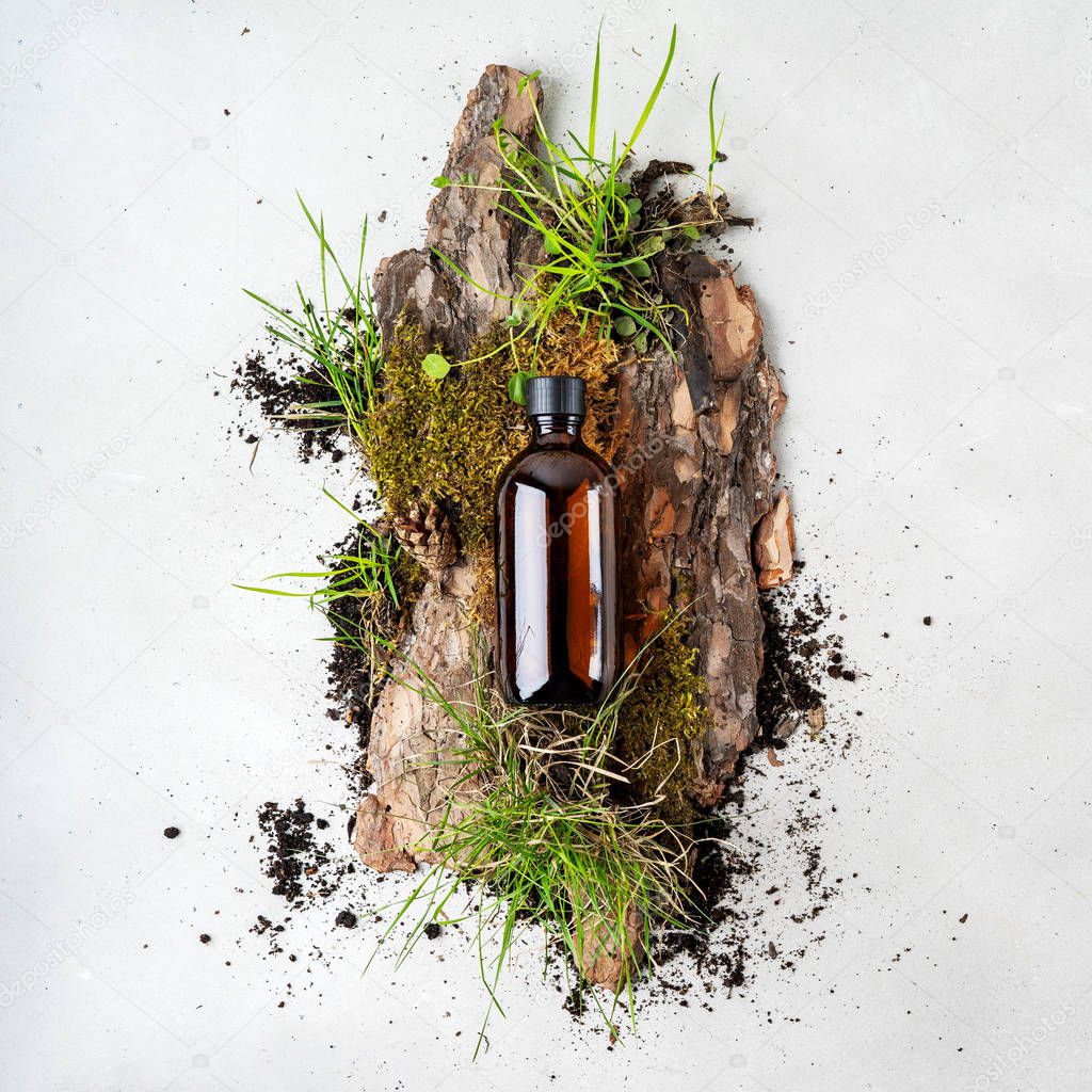 Bark tree with tiny mosses and grass and organic cosmetic products in glass brown bottle