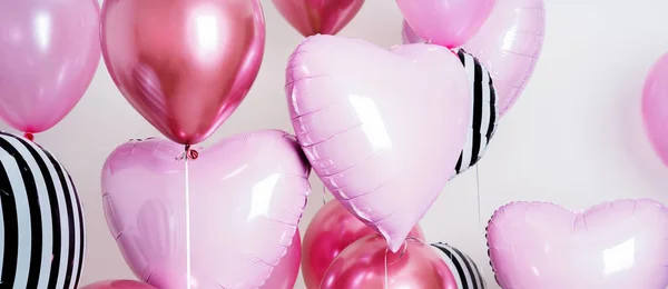 Set of pink and striped balloons in form of heart and round pink and striped on pastel pink background