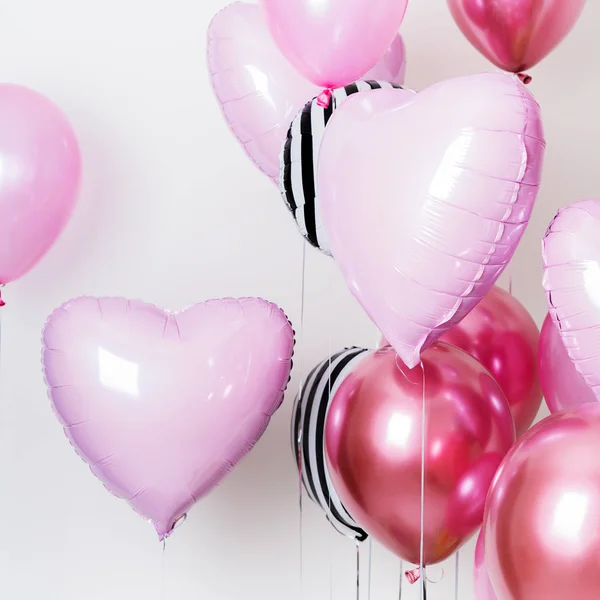 Set of pink and striped balloons in form of heart and round pink and striped on pastel pink background