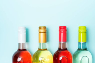 Mavi arka plan üzerinde beyaz ve gül şarap şişeleri Vidaşişe folyo kapaklar