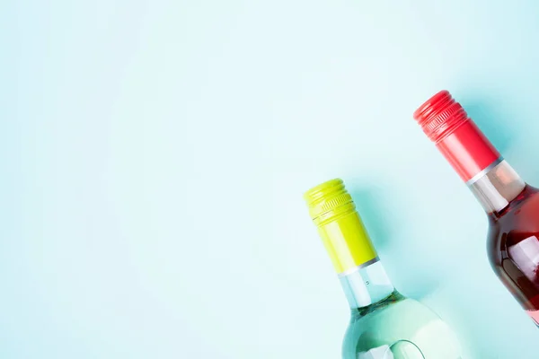 Screw bottle foil caps of white and rose wine bottles on blue background