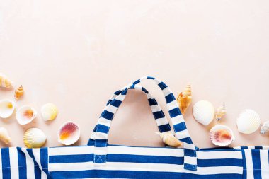 Pembe pastel arka planda kabukları ile çizgili plaj çantası