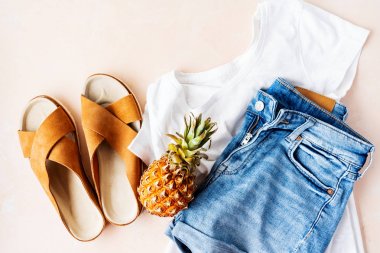 Beyaz t-shirt, kot şort ve pembe pastel arka plan üzerinde ananas ile trendy deri sandalet