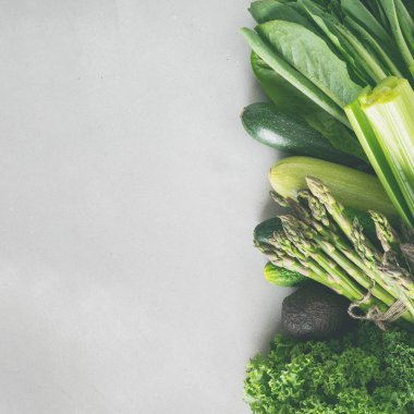 Gri beton arka plan üzerinde taze yeşil sebze ve yeşillik çeşitleri 