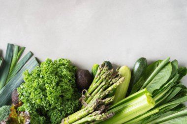 Gri beton arka plan üzerinde taze yeşil sebze ve yeşillik çeşitleri 