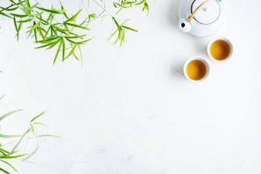 Çay ve çaydanlık iki beyaz bardak beyaz arka plan üzerinde yeşil yaprakları ile çevrili
