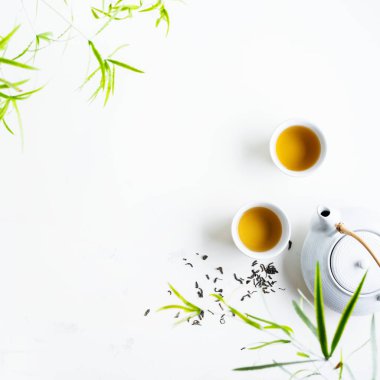 Çay ve çaydanlık iki beyaz bardak beyaz arka plan üzerinde yeşil yaprakları ile çevrili