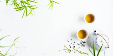 Çay ve çaydanlık iki beyaz bardak beyaz arka plan üzerinde yeşil yaprakları ile çevrili