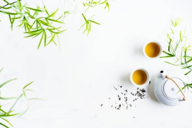 Çay ve çaydanlık iki beyaz bardak beyaz arka plan üzerinde yeşil yaprakları ile çevrili